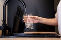 Close-up of a woman's hands pouring a glass of fresh water from the tap in the kitchen. Woman drinking a glass of Royalty Free Stock Photo