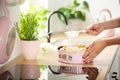 Close-up of woman`s hands sprinkling powdered sugar on a cake on a kitchen countertop