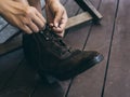 Close-up woman`s hands tying shoelace on the old leather boots in her legs. Royalty Free Stock Photo