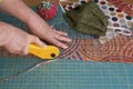 Close-up of a woman`s hands using a rotary cutter to cut leftover quilting fabric for hand sewn face masks