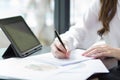 Close up of woman`s hands writing or signing in notepad placed on desktop with many documents Royalty Free Stock Photo