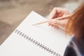 Close up of woman`s hands writing in spiral notepad placed on wooden desktop with various items. Vintage effect style pictures