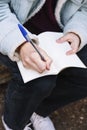 Close-up of a woman`s hands writing in a white notebook in the woods during winter season. Royalty Free Stock Photo