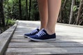 Close-up of a woman's legs in blue sneakers on a boardwalk footpath. Forest in the background. Brokenhead Wetland Trail.