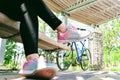 Close-up of woman's legs wearing gray-pink sneakers and black leggings. Bicycle, wooden canopy and concrete columns Royalty Free Stock Photo