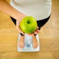 Close up of woman on scale holding fresh green apple in Diet and healthy lifestyle concept Royalty Free Stock Photo