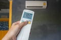 Woman set air conditioner temperature at 25 Degree Celsius by remote control at home for energy savings Royalty Free Stock Photo