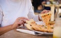 Close-up of woman sharing slice of delicious Italian pizza, sitting at table in a cozy outdoor pizzeria. Food background Royalty Free Stock Photo