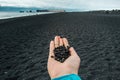 Close up woman showing handful of black pebbles on beach concept photo