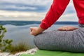 Close-up of the woman sitting in lotus position and meditating on the rock.