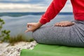 Close-up of the woman sitting in lotus position and meditating on the rock.