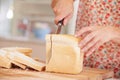 Close Up Of Woman Slicing Loaf Of Bread In Kitchen