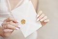 Close-up woman with slim body holding invitation envelope card in hands.