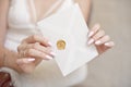 Close-up woman with slim body holding invitation envelope card in hands.