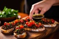 close-up of a woman spooning tapenade onto bruschetta