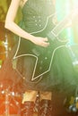 Close-up of a woman on stage playing on electro guitar. The girl rockstar in a black dress
