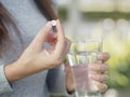 Close up of woman taking in pill with bokeh background.