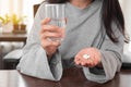 Close up woman taking pill and holding glass of water at home. woman taking medicine after doctor order Royalty Free Stock Photo