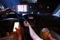 Close up of woman touching button on dashboard in car panel while driver holding a smartphone with blank screen in his