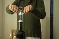 Close-up on a woman uncorking a bottle of red wine on a table