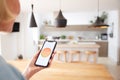 Close Up Of Woman Using App On Smart Phone To Control Central Heating Temperature In House