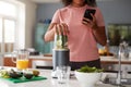 Close Up Of Woman Using Fitness Tracker To Count Calories For Post Workout Juice Drink She Is Making Royalty Free Stock Photo