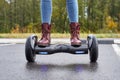 Close up of woman using hoverboard on asphalt road. Feet on electrical scooter outdoor