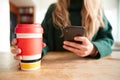 Close Up Of Woman Using Mobile Phone With Reusable Takeaway Drink Cup Sitting At Table  In Cafe Royalty Free Stock Photo