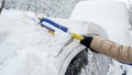 Woman using a snow brush to remove snow from her car\'s windshield after a heavy snowfall. Concept of winter weather Royalty Free Stock Photo