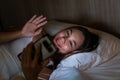 Close up of woman VDO call with smartphone late at night in bed. Bored and sleepless in dark room with moody lighting. In insomnia Royalty Free Stock Photo