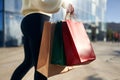 Close up of woman walking with shopping bags in hands in city from mall. Low angle view of girl going with purchases Royalty Free Stock Photo