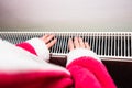 Close-up of a woman warming up her hands on a white radiator at home. Central heating concept Royalty Free Stock Photo