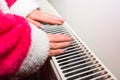 Close-up of a woman warming up her hands on a white radiator at home. Central heating concept Royalty Free Stock Photo