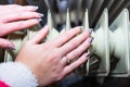 Close-up of a woman warming up her hands on a white radiator at home. Central heating concept Royalty Free Stock Photo