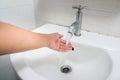 Woman wash her left hand at faucet basin in bathroom Royalty Free Stock Photo