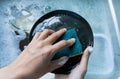 Close-up of a woman washing dishes with dirty food scraps Cleaner in the sink the kitchen counter at home Royalty Free Stock Photo