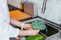 Close up woman washing fresh raw broccoli under running water over sink on her kitchen. Preparing food ingredients for Royalty Free Stock Photo