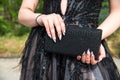 Close-up of a woman wearing a formal black dress, her hands with an attractive manicure, holding a glittering handbag. Royalty Free Stock Photo