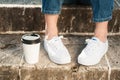 Close-up of woman wearing jeans and sneakers standing near coffee