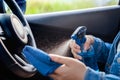 Close up woman wearing mask applying spray alcohol with microfiber cleaning interior car and steering wheel