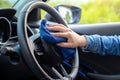 Close up woman wearing mask applying spray alcohol with microfiber cleaning interior car and steering wheel