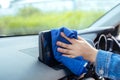 Close up woman wearing mask cleaning screen with microfiber on interior car protection germs