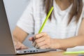 Close up of a woman wearing a white shirt and holding the pen and placing her hand near the grey laptop computer keyboard Wooden Royalty Free Stock Photo