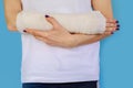 Woman with broken arm bone in cast, plastered hand on blue background. Royalty Free Stock Photo