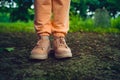 Close up of woman& x27;s feet in shoes on ground. Woman in pink sneakers stands in park in summertime.