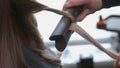 Close-up of a woman& x27;s hand curling her hair with a flat iron. Beautiful girl at the hairdresser. Beauty salon