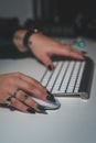 Close-up of a woman's hand with green-painted nails and silver jewelry holding a computer mouse, Royalty Free Stock Photo