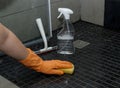 Close up of woman& x27;s hand in orange gloves cleaning dirty shower floor tiles