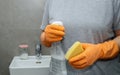 Close up of woman& x27;s hand in orange gloves holding a yellow sponge and a cleaning spray bottle Royalty Free Stock Photo