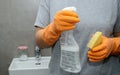 Close up of woman& x27;s hand in orange gloves holding a yellow sponge and a cleaning spray bottle Royalty Free Stock Photo